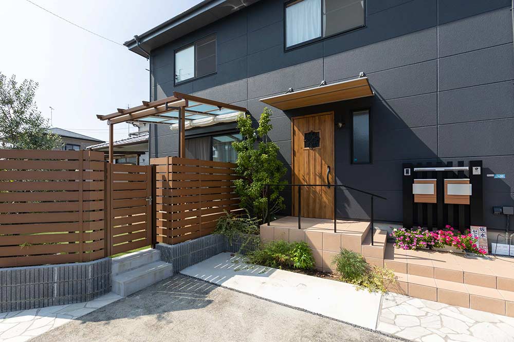 深い色の外壁に木調の玄関ドアが映える外観