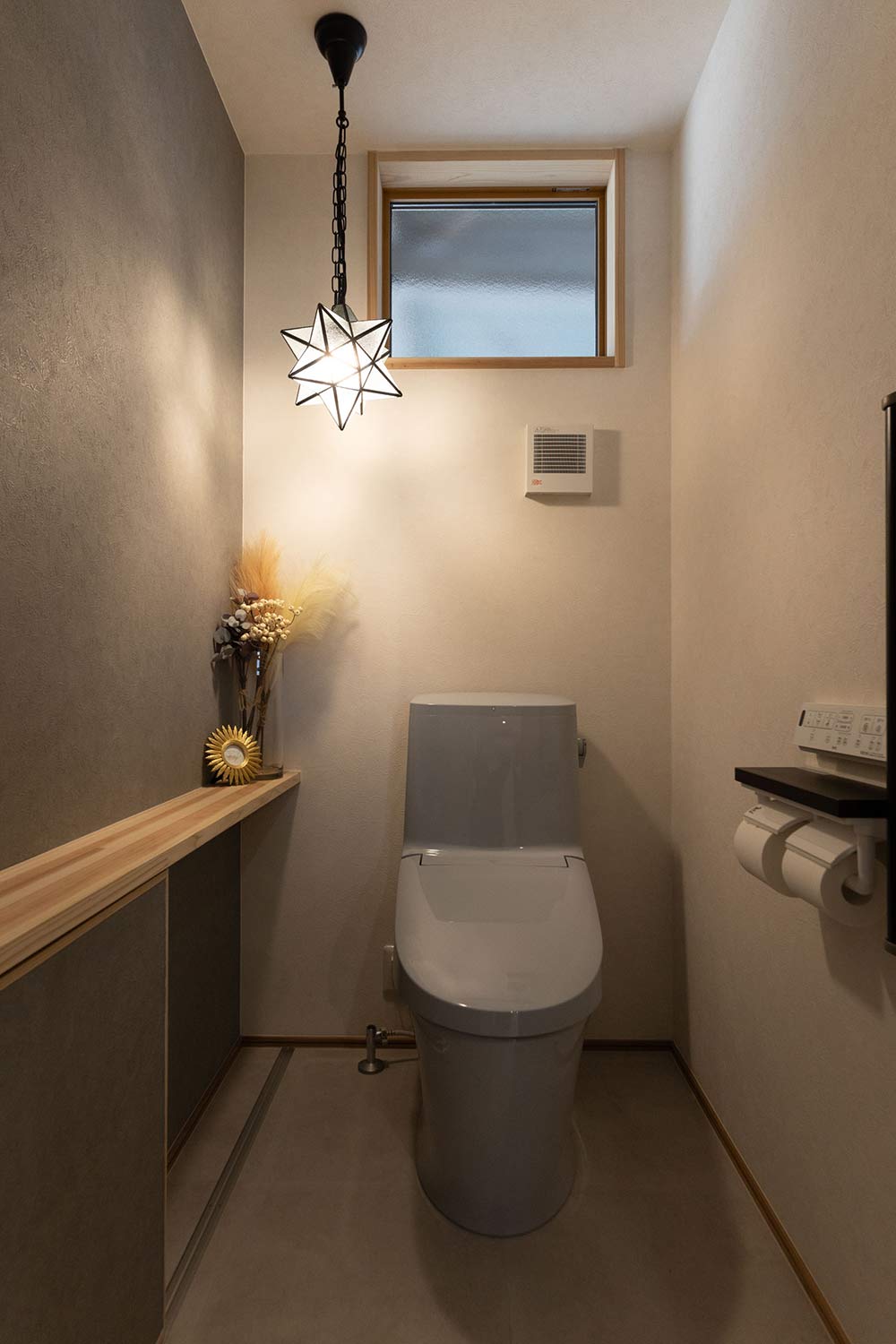 グレーのアクセントクロスと木のカウンターが織りなす、上質な落ち着き感のあるトイレ